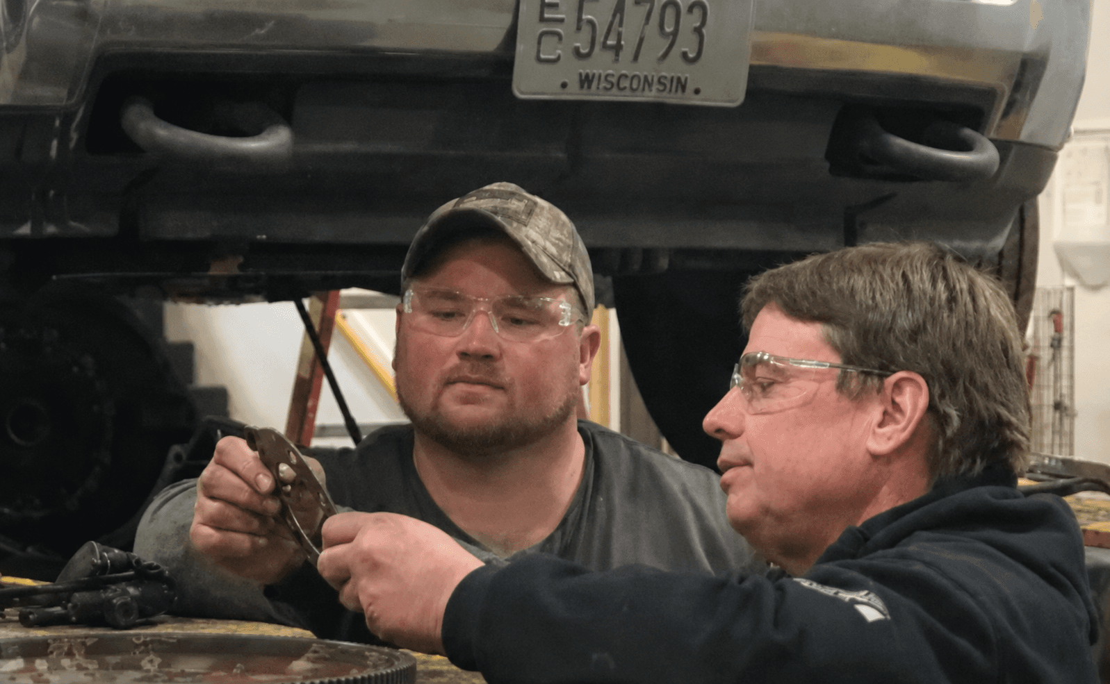 Expert technicians inspecting truck components with safety goggles
